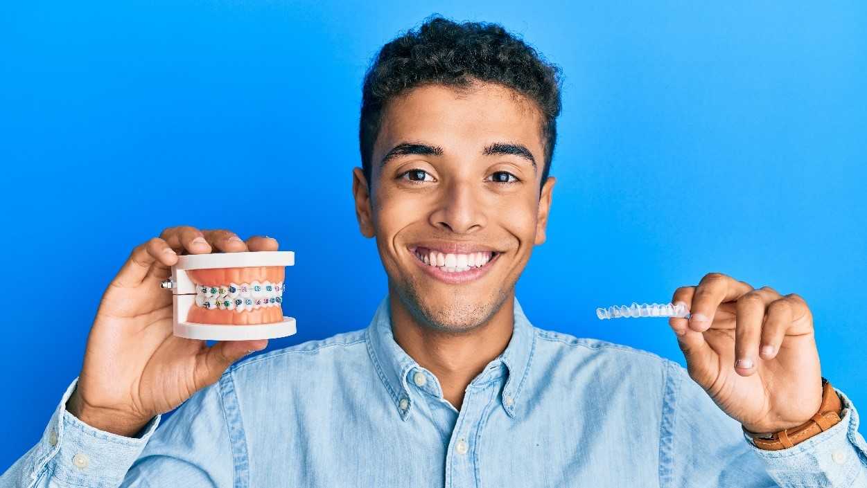 Man holding braces and Invisalign to compare